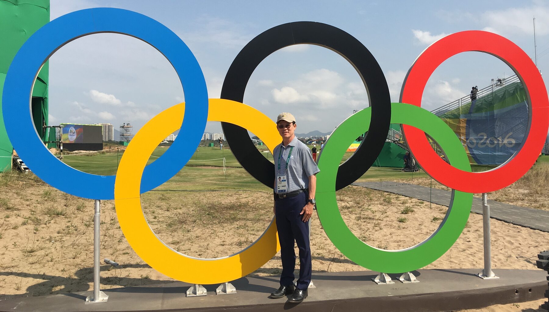 Jittisak Tamprasert beside the Olympic rings at a golf venue.