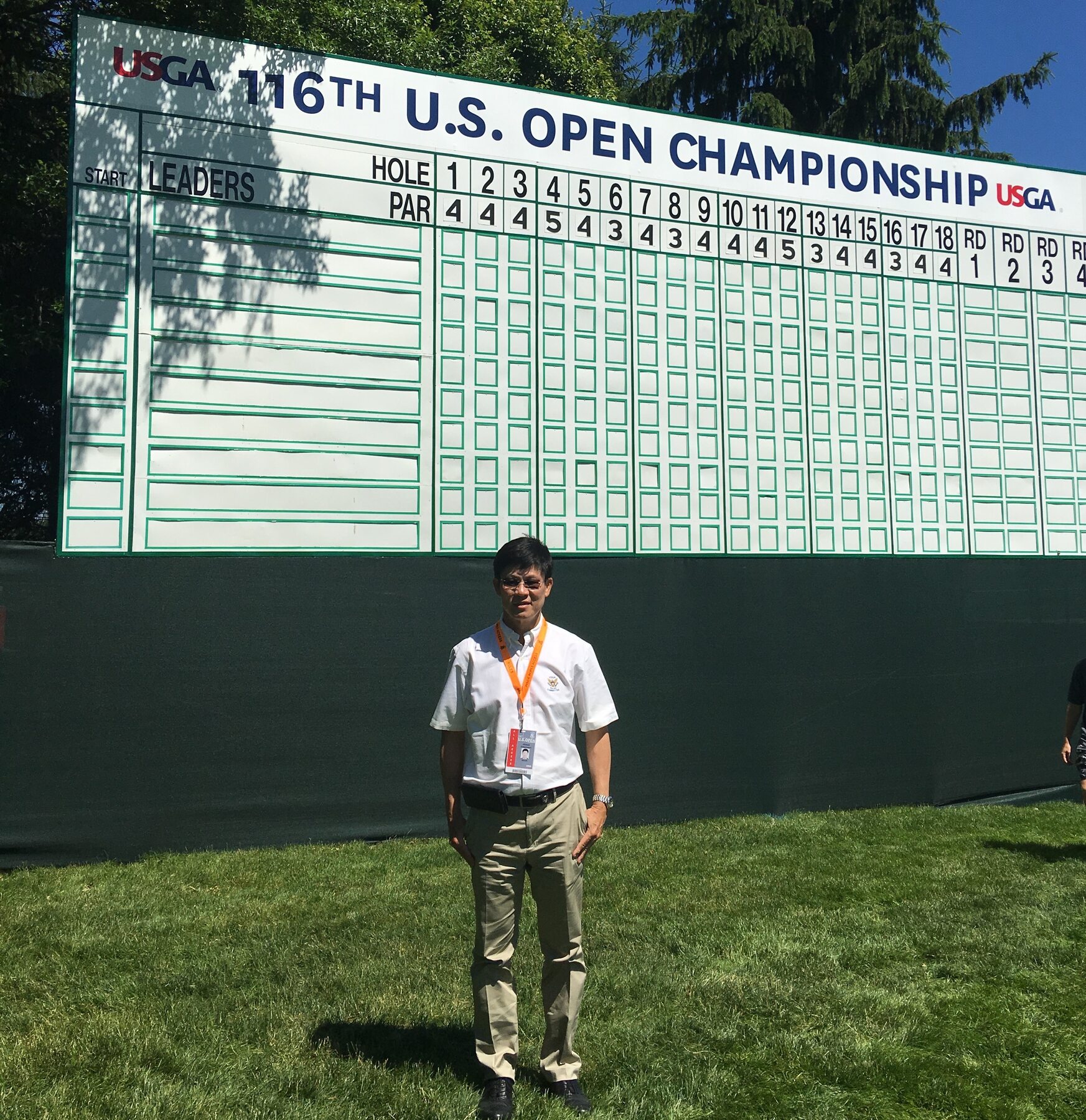 Jittisak Tamprasert in front of the U.S. Open Championship scoreboard.